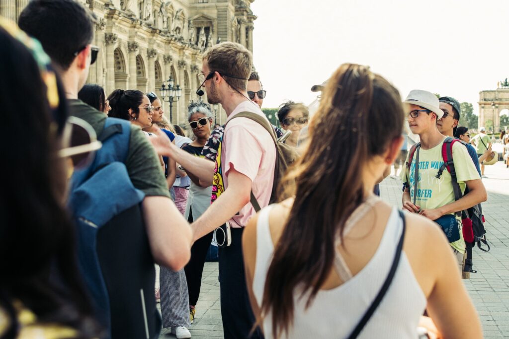 A tour guide standing outside of a building with a group, all wearing headsets.